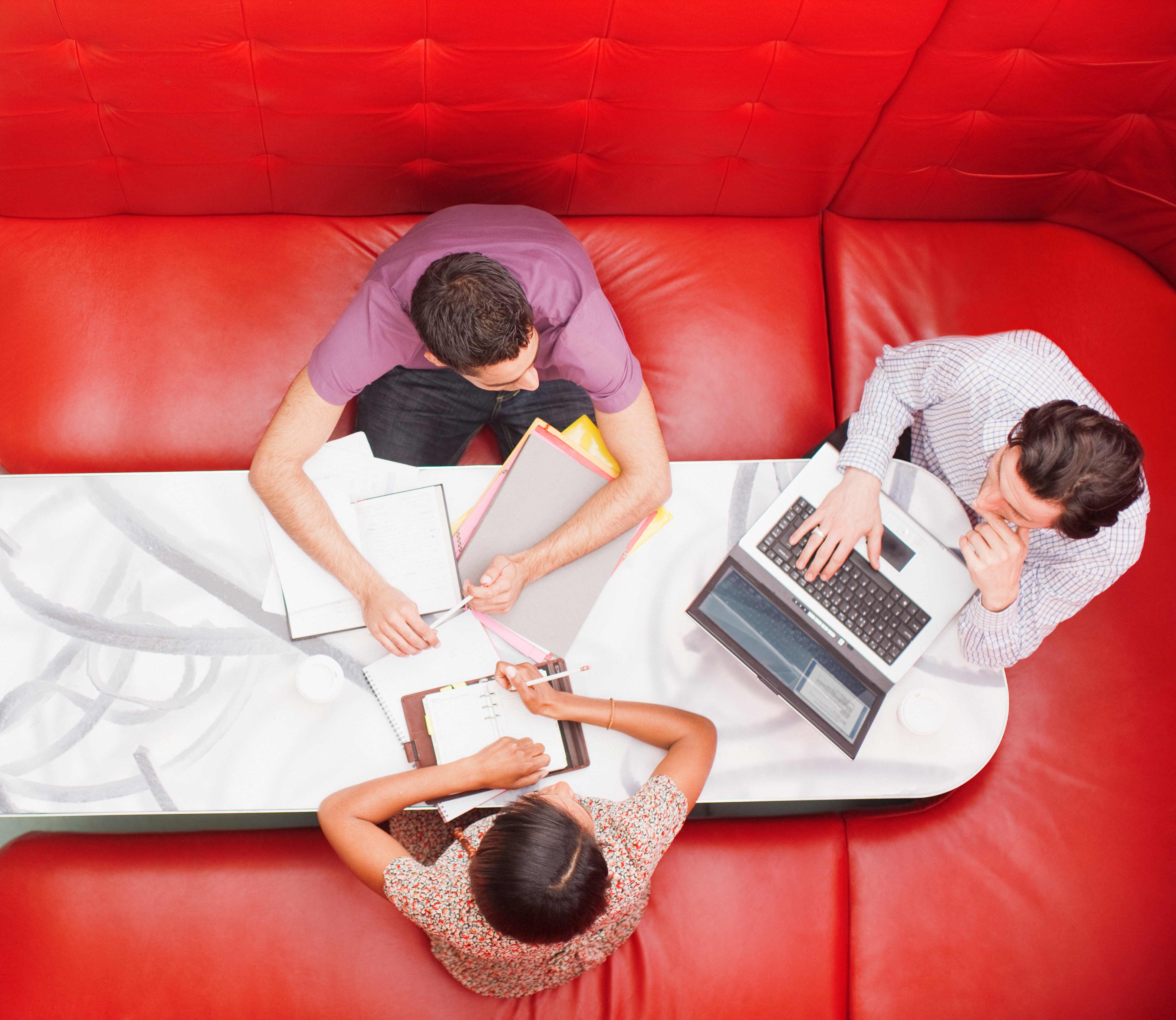 Team collaborating around table with red seating